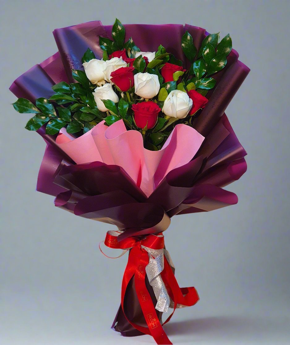 Elegant bouquet of purple, pink, red, and white roses with lush green fillers, tied with a red ribbon—perfect for romantic gestures.