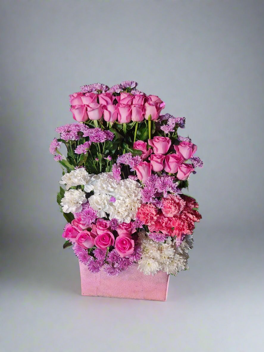 Discover a beautiful floral arrangement with pink roses, white-pink carnations, and purple daisies elegantly arranged in a box. Perfect for gifting on any occasion, this stunning combination radiates love, grace, and vibrancy.