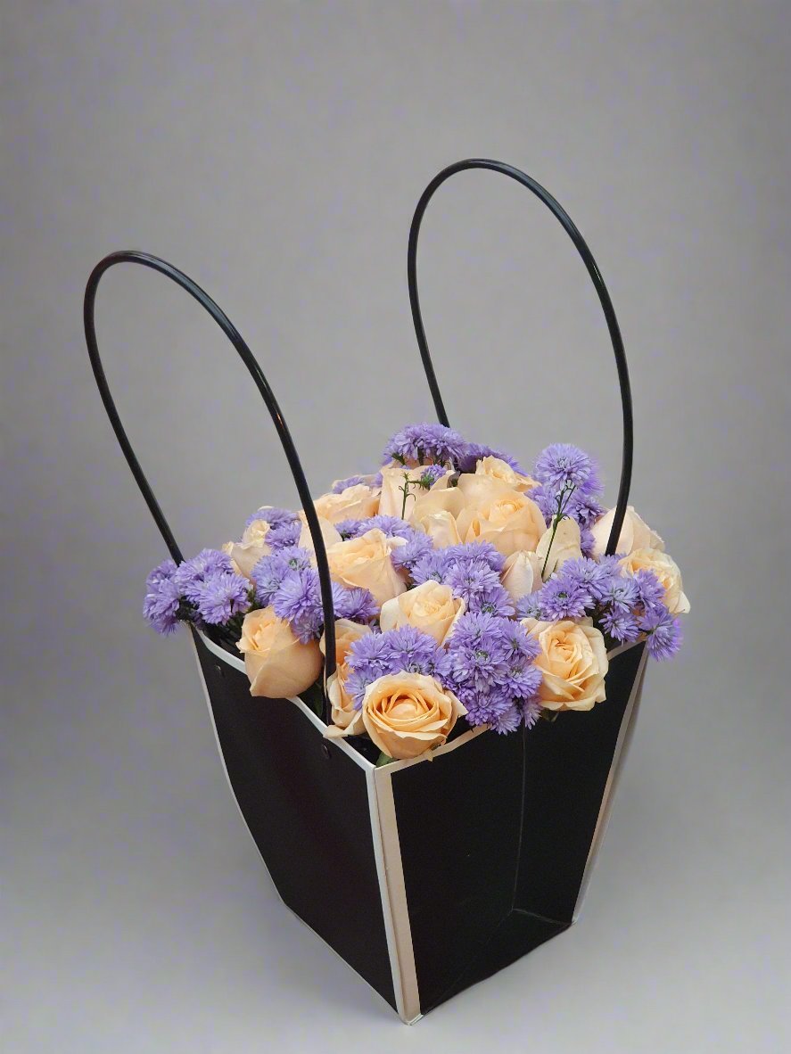 Discover the enigmatic charm of a black box surrounded by vibrant purple carnations and yellow roses, blending mystery with floral elegance.