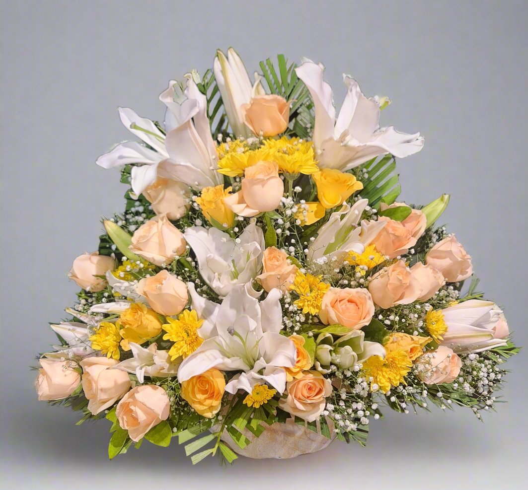 A stunning floral arrangement featuring white lilies, yellow roses, peach roses, and yellow daisies with fillers. This vibrant bouquet symbolizes beauty, love, and joy, making it an ideal gift for any occasion.