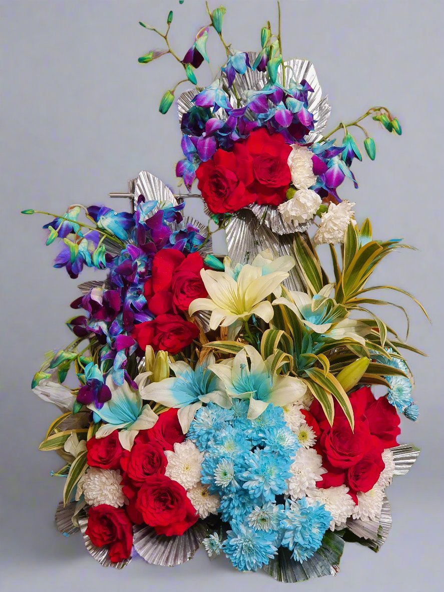 Striking floral arrangement with red roses, blue orchids, and white lilies accented with silver leaves—a bold, elegant centerpiece for special occasions.