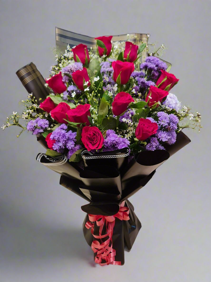 A captivating black bouquet featuring vibrant purple daisies, rich red roses, and delicate fillers. This elegant and sophisticated floral arrangement makes the perfect gift for expressing love and admiration.