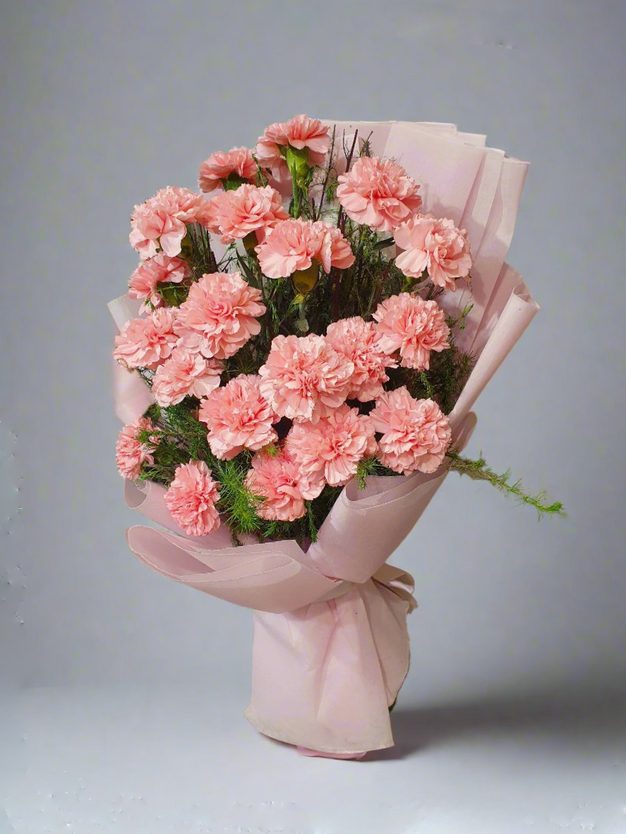 Explore the elegance of a pink carnation bouquet adorned with lush green leaves. Perfect for any occasion, adding charm and natural beauty.