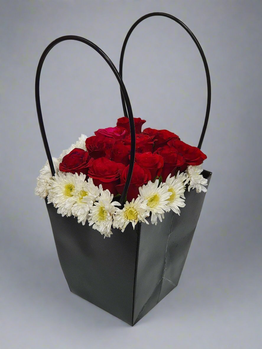 An elegant black box surrounded by red roses and white daisyfillers. A perfect blend of bold passion and graceful purity for special moments.