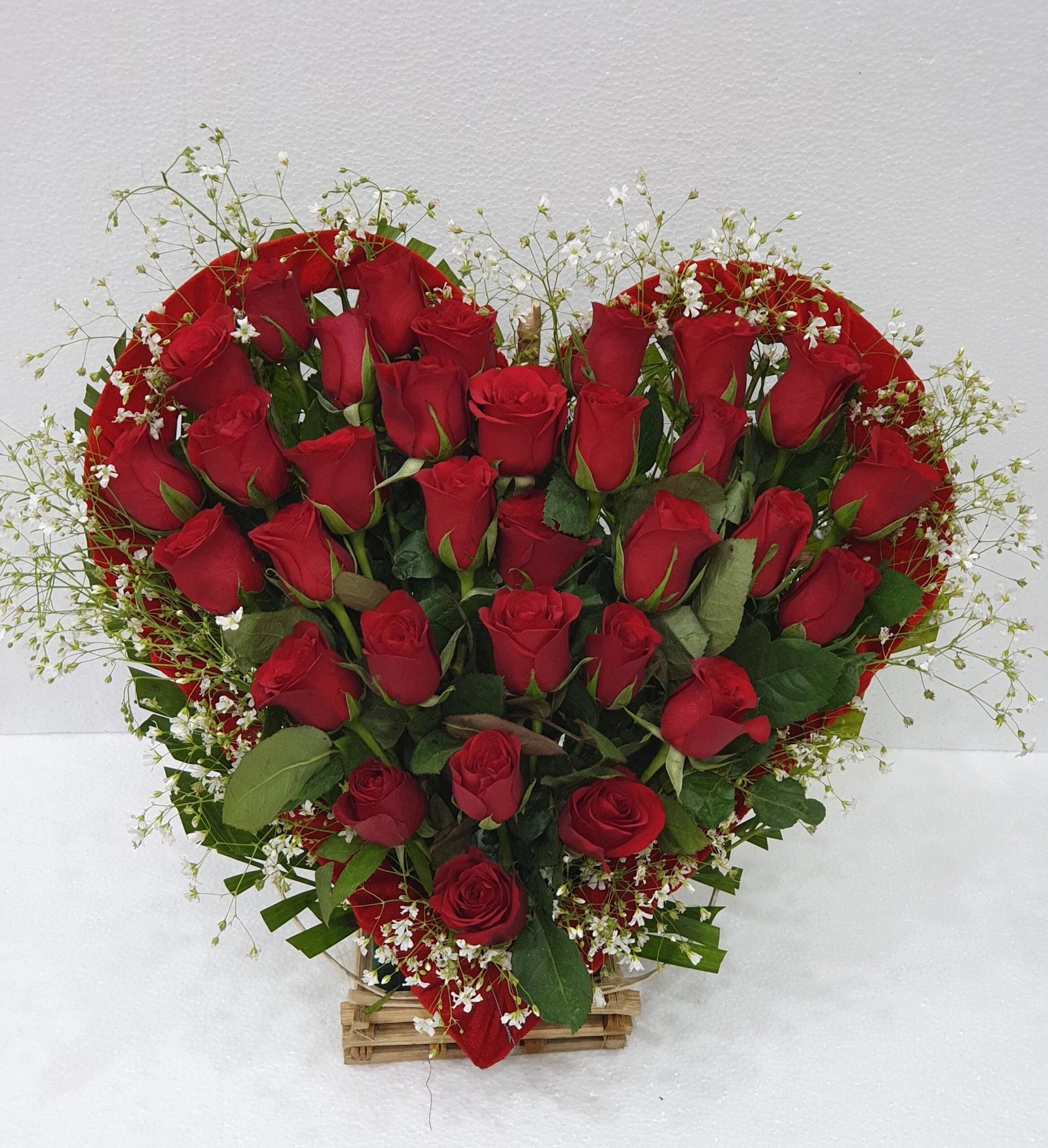 Discover a beautiful heart-shaped arrangement of red roses and green fillers, perfect for expressing love on special occasions.