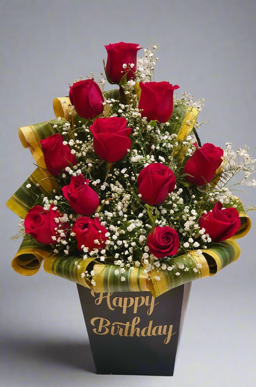 Celebrate a birthday with 12 red roses in a black box, accented with white and green fillers for a sophisticated, romantic gift.