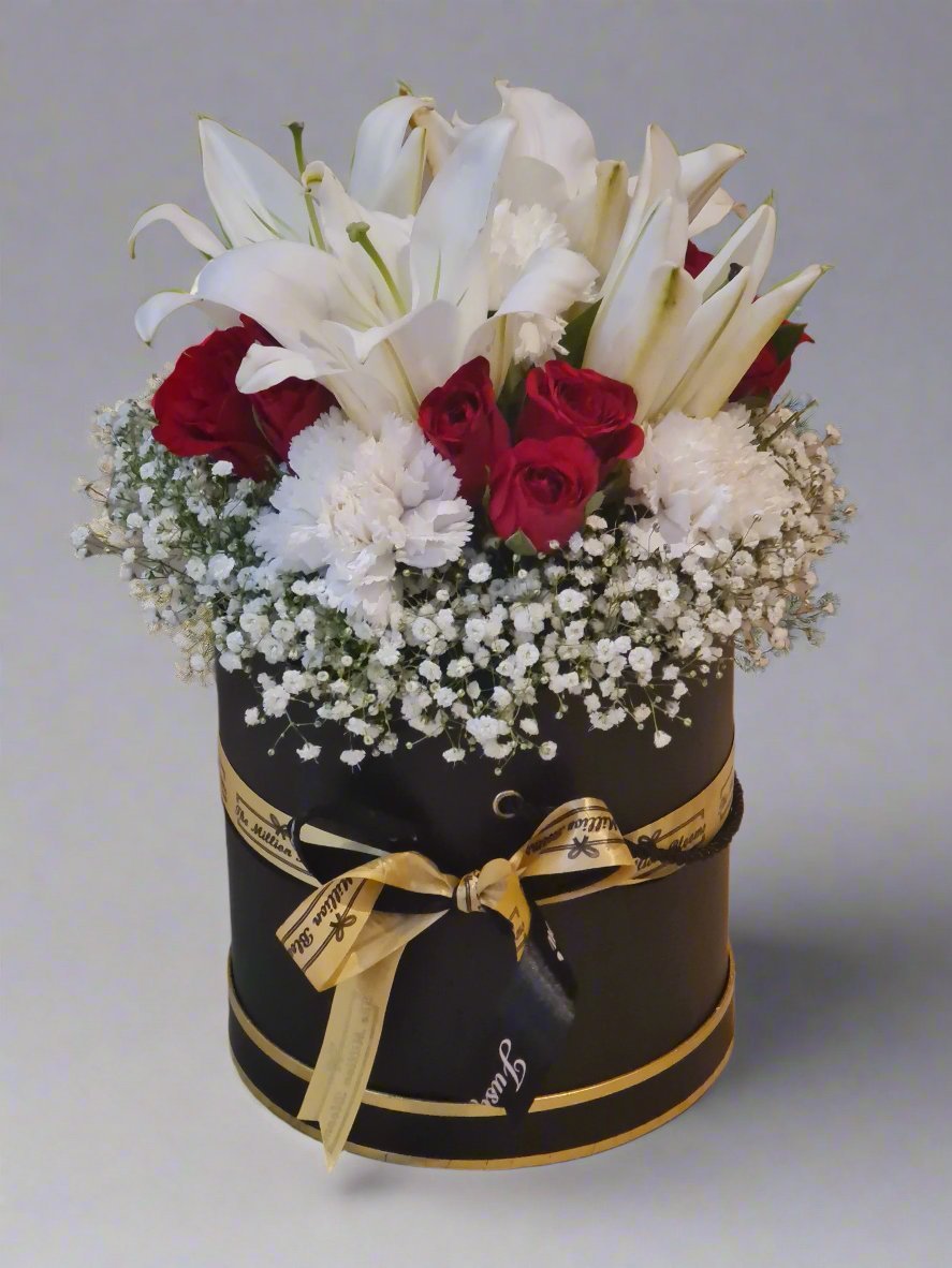 A luxurious arrangement of red roses, white lilies, and white carnations inside a black box. Perfect for any special occasion, this elegant floral design adds a touch of sophistication.