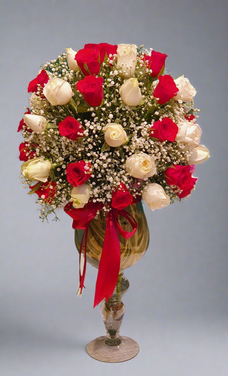 A standing bouquet of red and peach roses, with green foliage and white fillers, creating a vibrant and elegant floral display. Perfect for any occasion.