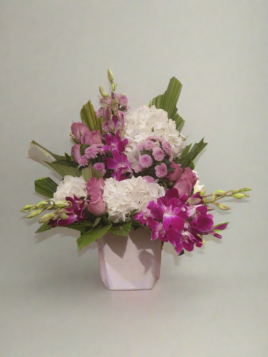 Elegant arrangement of pink roses, white carnations, pink daisies, and pink orchids for a charming and harmonious floral display.