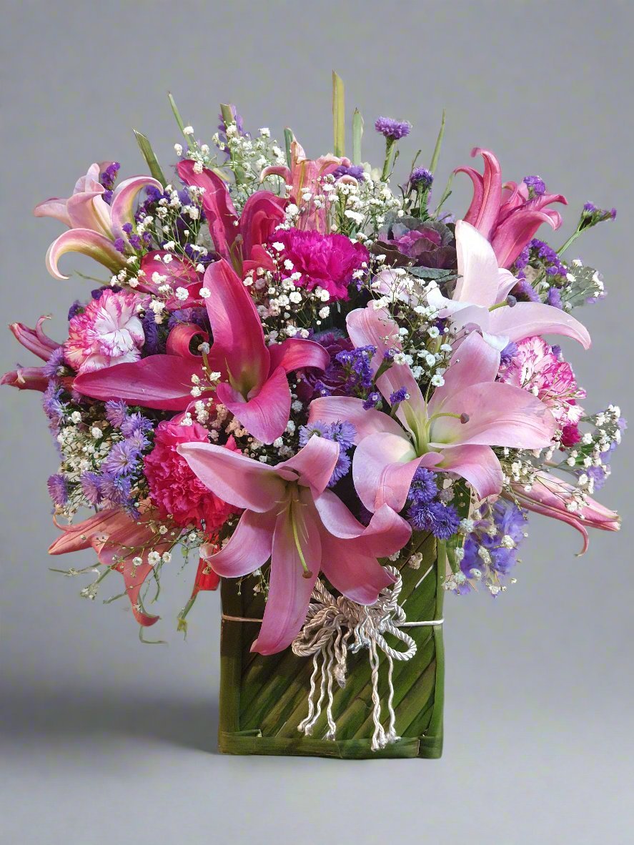 A lush green box filled with elegant lilies, charming carnations, and vibrant seasonal fillers for a stunning floral arrangement.