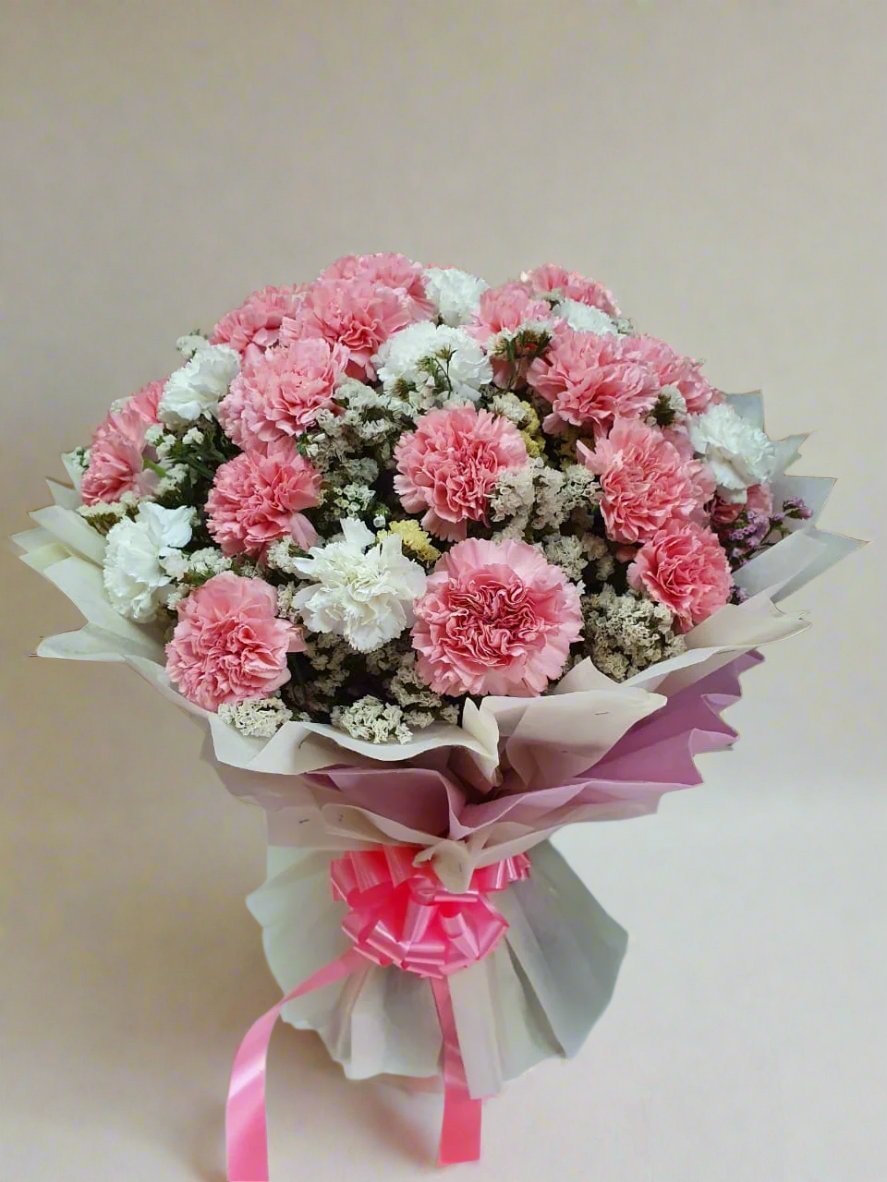 Elegant pink and white carnation bouquet with green fillers, wrapped in white paper. Perfect for all occasions. Brighten any day with this timeless gift.