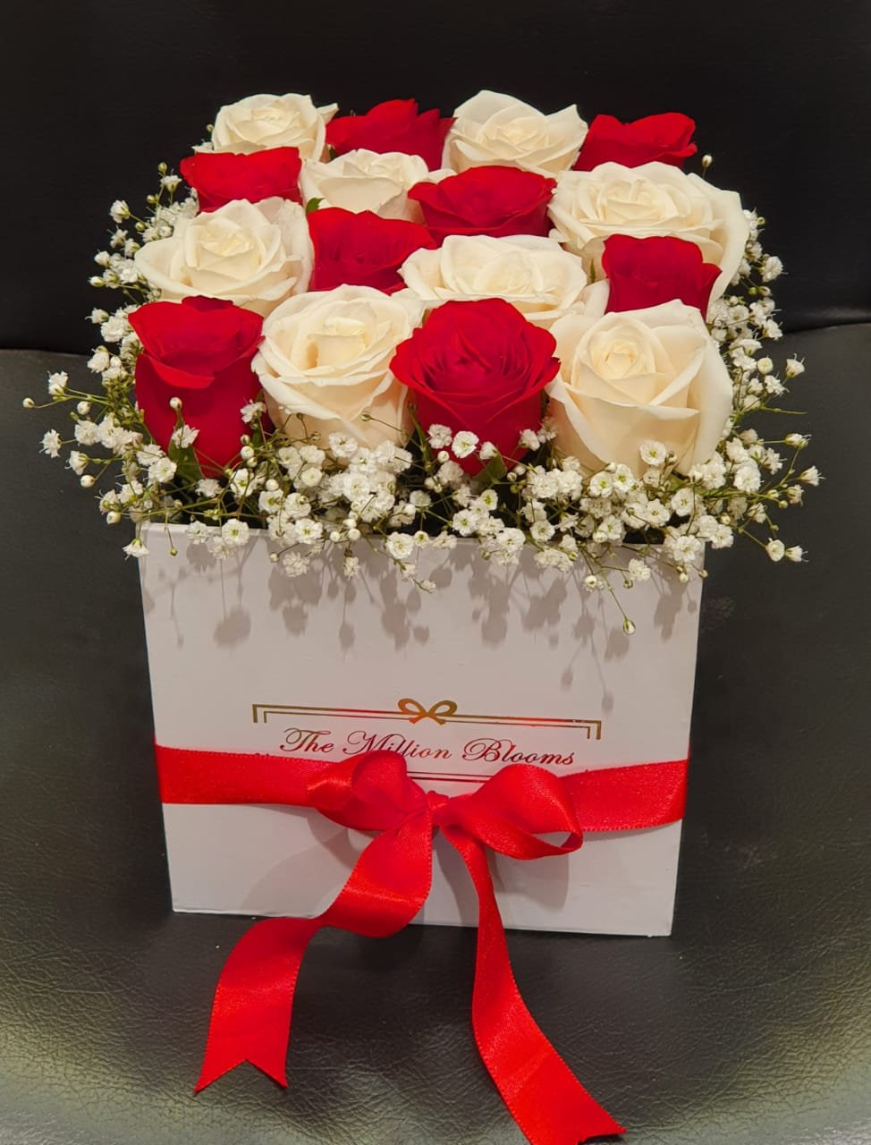 A stunning arrangement of red and peach roses in a box, accented with fresh greenery. Perfect for any special occasion or heartfelt gesture.