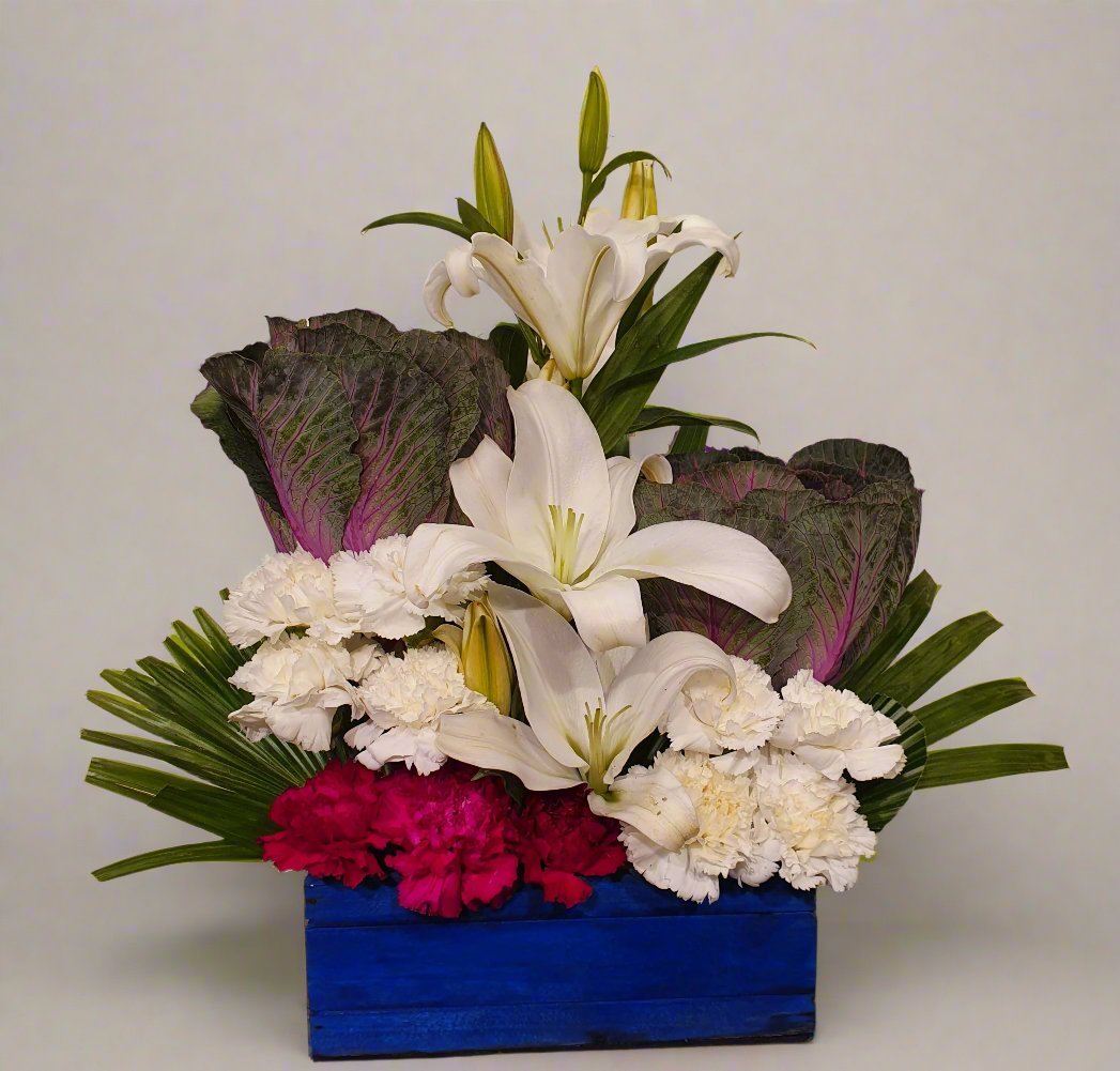 Add elegance to any space with our white lilies, pink carnations, and lush greenery arrangement in a stunning blue base.