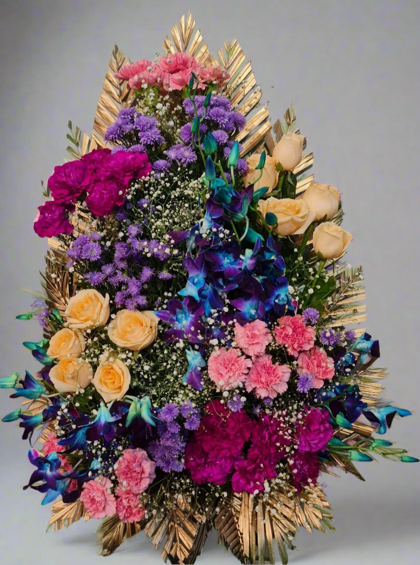 A vibrant floral arrangement with peach roses, pink carnations, orchids, and golden palm leaves, perfect for grand celebrations or special occasions.