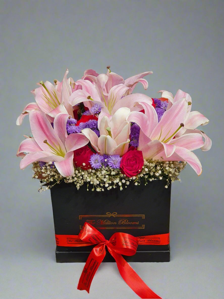 Elegant black box filled with pink lilies, vibrant red roses, and cheerful purple daisies, perfect for gifts or décor. Order stunning floral arrangements!