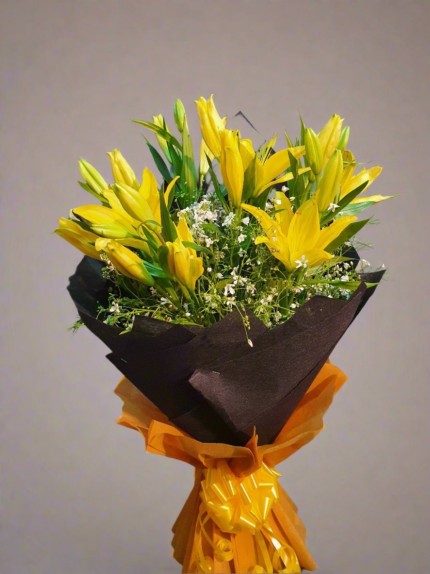 Brighten any occasion with our vibrant yellow lily bouquet, accented with baby's breath and wrapped in elegant black and gold.